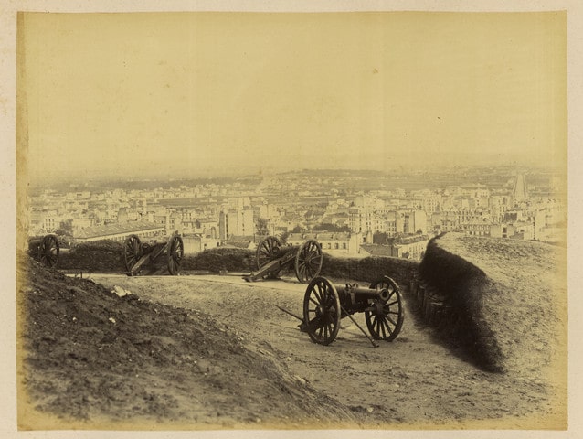 Black and White contemporary photograph by Bruno Braquehais of four cannons on Montmartre Hill overlooking Paris. The cannons aim in different directions over Paris.