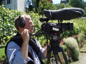 The documentary film maker stephen Macmillan seen filming with camera and sound recording equipment in the Clos Montmartre vineyard.