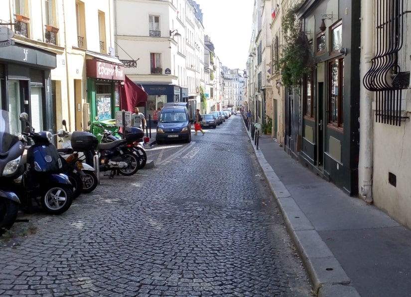 Rue des Trois Freres Montmartre showing a straight street with a steady incline. The street is fairly narrow and cobbled apartment blocks and small businesses line the streets the buildings are about five stories high.