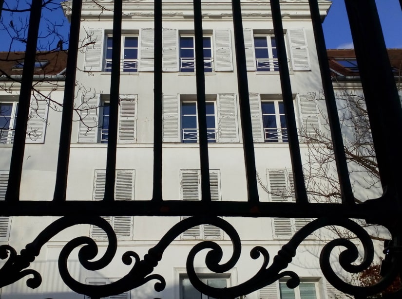 The Sandrin Folly a three story 18th century white classical building seen through ornate railings. Rue Norvins Paris 75018