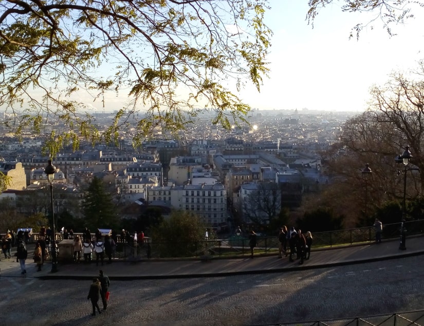 View of Paris from the Montmartre Hill. Viewpoint is from on front of Sacré Coeur church. Distant Paris rooftops are lit up by weak winter sun