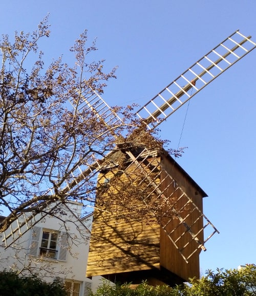 The Radet windmill framed against a clear blue sky over the entrance to the Moulin de la Galette restaurant Rue Lepic Paris 75018