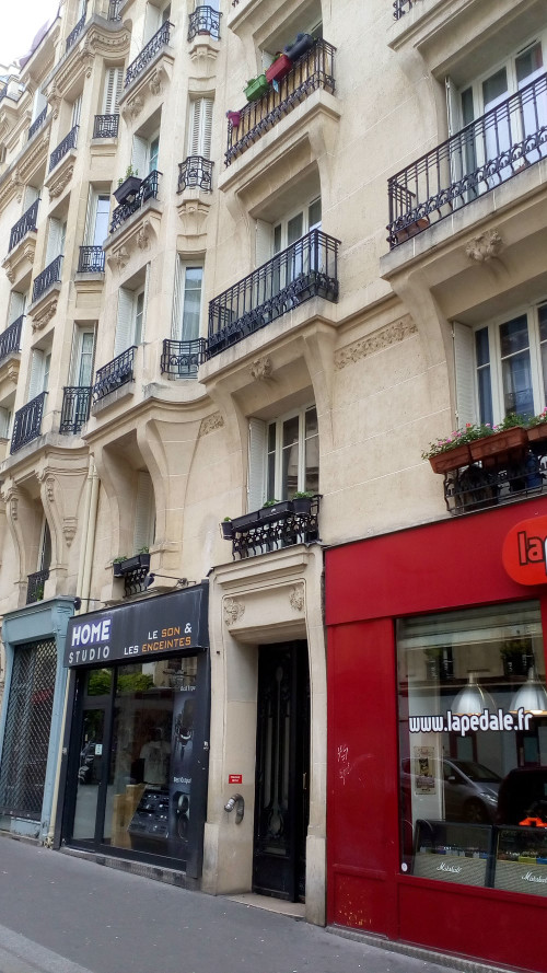 A rich bourgeois apartment building with wrought iron balconies, flower boxes and bow windows. The building is constructed from light coloured stone. Two small shop fronts flank the entrance to the building. The site at 37 Rue Victor Massé Montmartre of Degas’ apartment and studio to 1912.