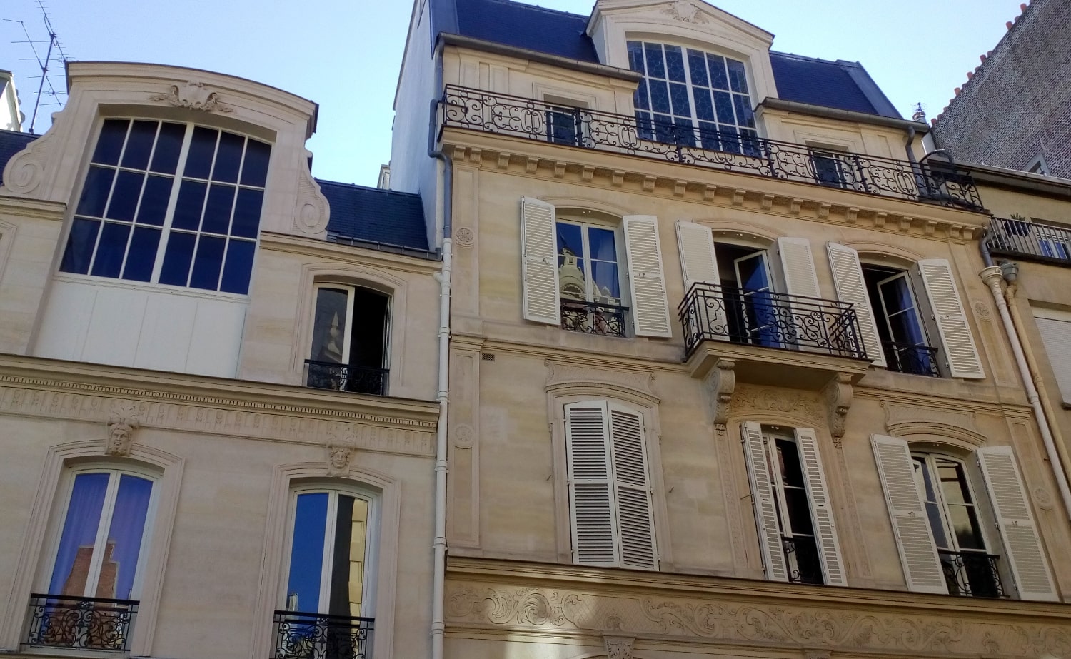 Photograph of 23 Rue Ballu Paris 75009. We see an apartment facade with large artist studio type windows on the upper floors of the building. Edgar Degas lived and worked here from 1890 – 1897.